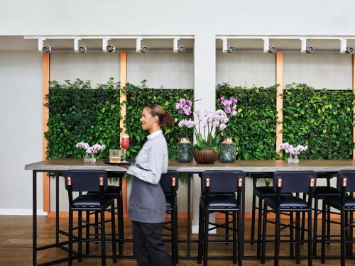 a man standing in front of a table with chairs at Hyatt House Manchester - Aparthotel in Manchester