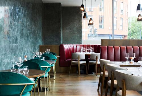 a restaurant with tables and chairs and a red couch at Hyatt House Manchester - Aparthotel in Manchester
