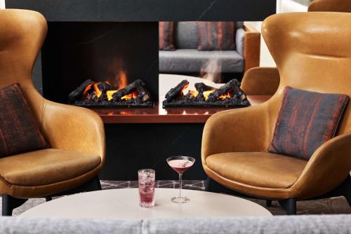 a glass of wine sitting on a table in front of a fireplace at Hyatt House Manchester - Aparthotel in Manchester