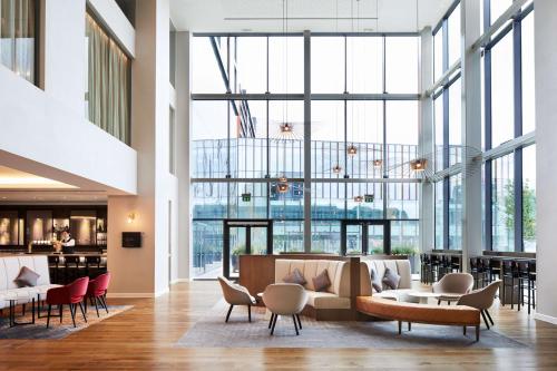 a lobby with chairs and tables and large windows at Hyatt House Manchester - Aparthotel in Manchester