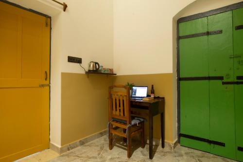 a room with a desk with a computer and a green door at Craft Hostels in Anjuna