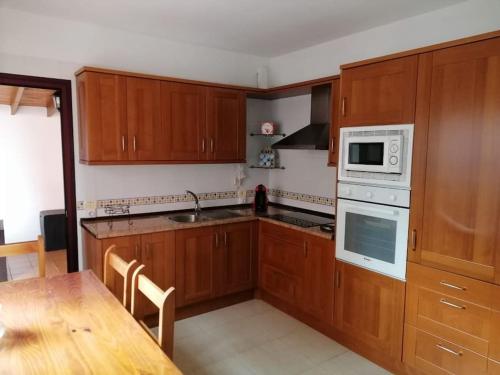 a kitchen with wooden cabinets and a table and a microwave at Idílico adosado en El Mocanal in Mocanal