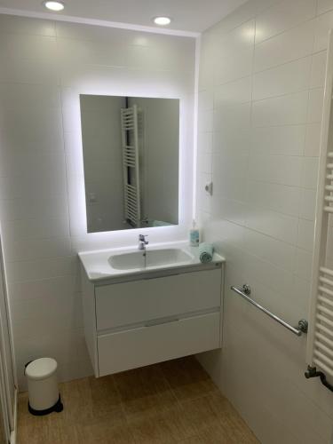a white bathroom with a sink and a mirror at Amazing in front of the sea apartment in Comarruga