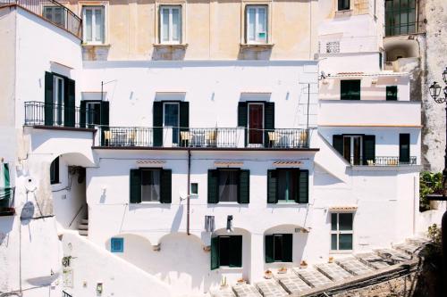a white building with black windows and balconies at Maison Escher in Atrani