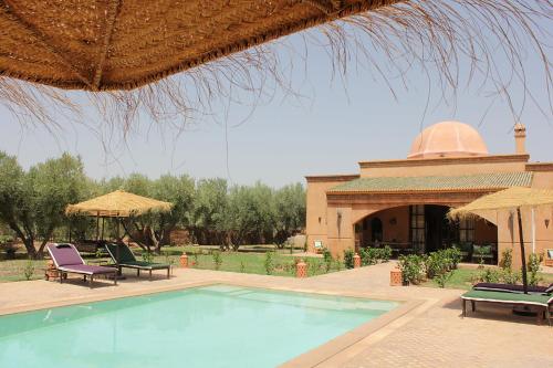 a swimming pool with chairs and umbrellas next to a building at Villa Serena Marrakech - Maison d'hôtes in Marrakech