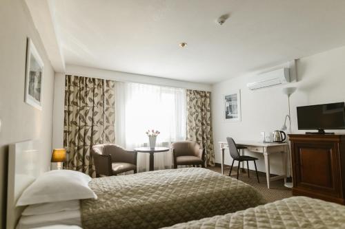 a hotel room with two beds and a table with chairs at Villa Helvetia in Târgu-Mureş