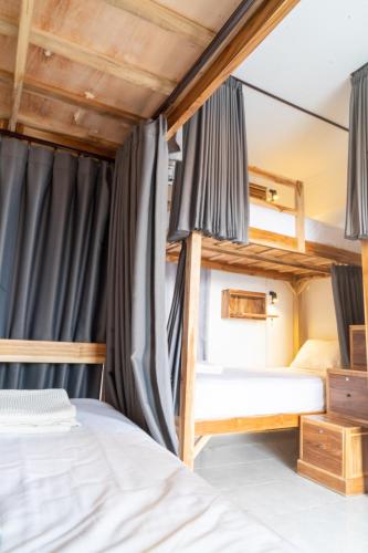 two bunk beds in a room with blue drapes at Surf & Party - Hostel Somewhere Else in Canggu
