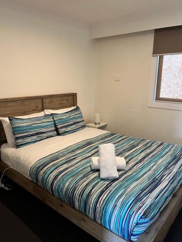 1 dormitorio con 1 cama con 2 toallas en Snow View Holiday Units, en Mount Beauty