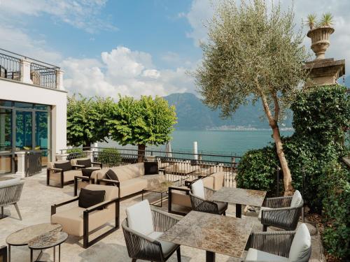 a patio with tables and chairs and a view of the water at MUSA Lago di Como in Sala Comacina