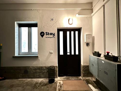 a black door in a room with a window at Stay in Malpensa in Case Nuove