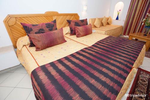 a bedroom with a large bed with colorful pillows at Hotel Golf Residence in Hammam Sousse