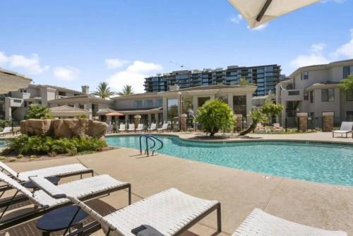 a swimming pool with chairs and buildings in the background at The Nines Scottsdale in Scottsdale