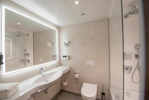 a bathroom with a sink and a toilet and a mirror at Insel-Hotel Heilbronn in Heilbronn