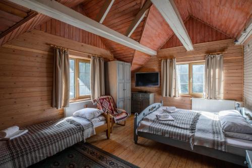 1 dormitorio con 2 camas y TV en Маєток Ліс і Гори en Bukovel