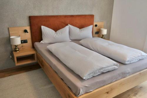 a large bed with white sheets and pillows on it at BioTop Appartement Kronplatz in Perca
