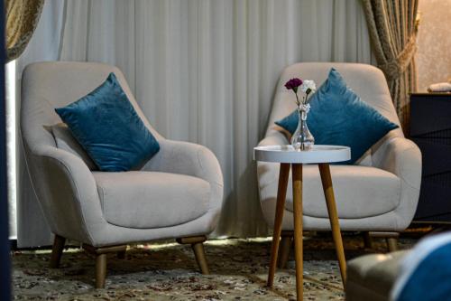 two chairs and a vase with a flower on a table at The Castle Hotel in Amman