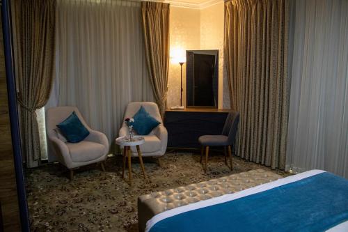 a hotel room with a bed and two chairs and a television at The Castle Hotel in Amman