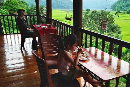 a little girl sitting at a table on a porch at Ba Be lake-Huyền Hào Homestay in Ba Be18