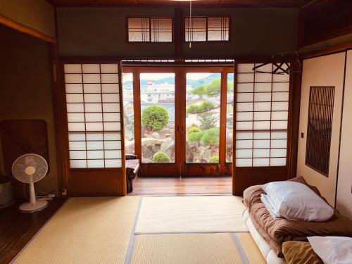 Pokój z pokojem z drzwiami i oknem w obiekcie Guest House Toranjyo-lit w mieście Tamano