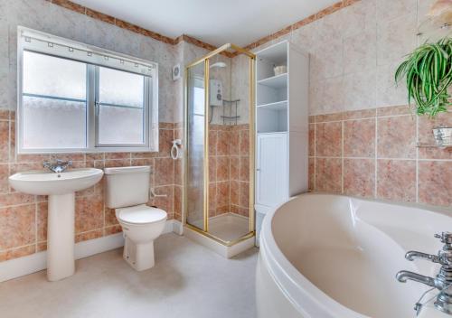 a bathroom with a tub and a toilet and a sink at 2 Benhall Green in Saxmundham
