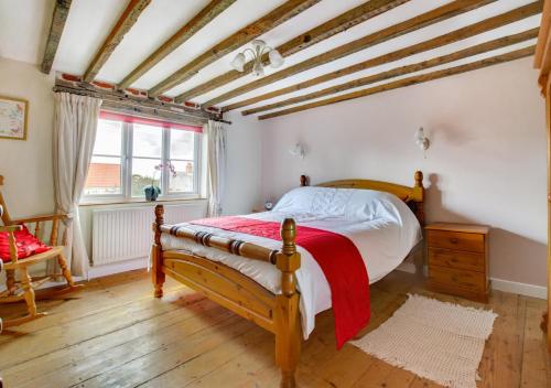a bedroom with a wooden bed in a room with a window at 2 Benhall Green in Saxmundham
