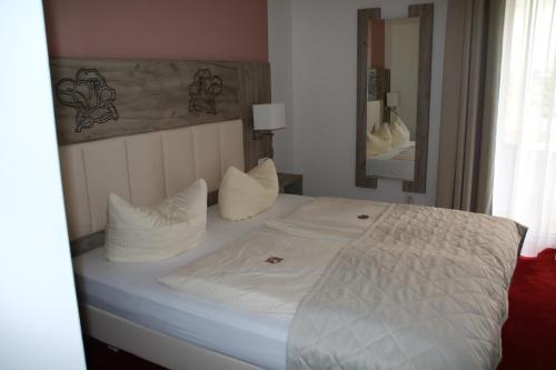 a bedroom with a bed with white sheets and pillows at Hotel Rosengarten in Bad Salzuflen