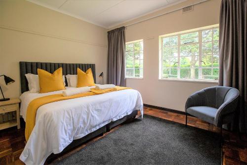 een slaapkamer met een bed met gele kussens en een stoel bij #9 Notties Avenue in Nottingham Road