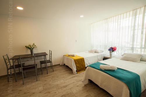 a room with two beds and a table and a desk at ApartaSuites Bogota Toscana in Bogotá