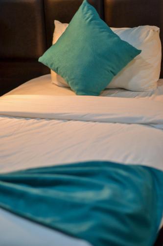 a bed with a green pillow on top of it at The Castle Hotel in Amman