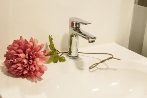 a bathroom sink with a faucet and a pink flower at ApartaSuites Bogota Toscana in Bogotá