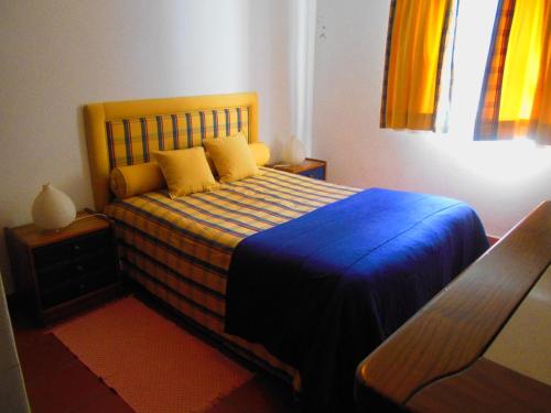 1 dormitorio con 1 cama con sábanas azules y almohadas amarillas en Casa de Campo 1, en Lavre