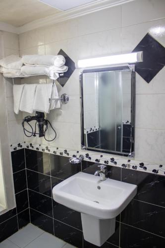 a bathroom with a sink and a mirror and towels at The Castle Hotel in Amman
