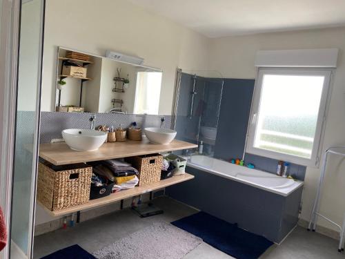 La salle de bains est pourvue de 2 lavabos et d'une baignoire. dans l'établissement Maison cosy Arnage, à Arnage