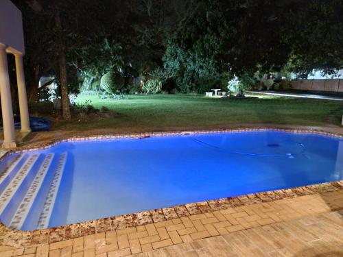 a large blue swimming pool in a yard at night at Crayfish Creek Guest House in Richards Bay