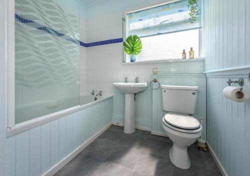 a bathroom with a toilet and a tub and a sink at Bryn in Abersoch