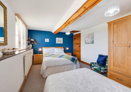 LlangurigにあるBryncyllaの青い壁のベッドルーム1室(ベッド2台付)
