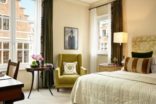 a bedroom with a bed and a chair and windows at Rocco Forte Hotel Amigo in Brussels