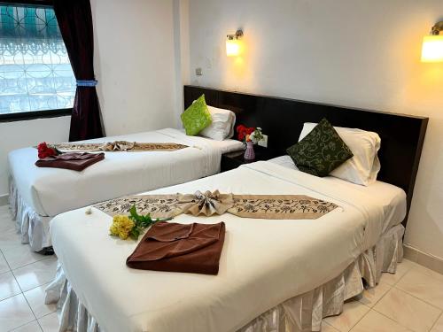 2 Betten in einem Hotelzimmer mit Blumen darauf in der Unterkunft Lamai Apartment in Patong Beach