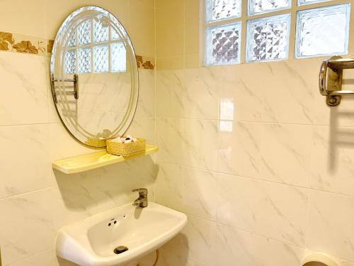 a white bathroom with a sink and a mirror at Lamai Apartment in Patong Beach