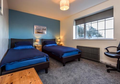 a bedroom with two beds and a window at Drws y Llan in Llanengan