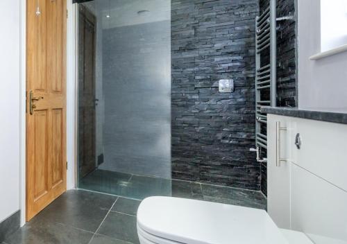 a bathroom with a toilet and a stone wall at Drws y Llan in Llanengan