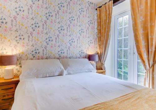 a bedroom with a bed with a floral wallpaper at The Barn in Llanerchymedd