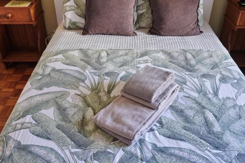 a bed with a blanket with a towel on it at Ljmonade Hostel in Cascais