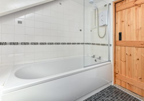 a white bath tub in a white tiled bathroom at Ty Ni in Nefyn