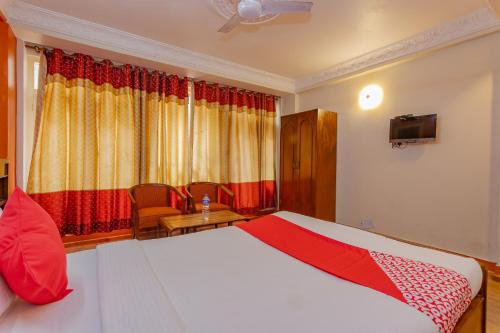 加德滿都的住宿－OYO 795 Hotel Holiday Inn，卧室配有一张床和一张桌子及椅子
