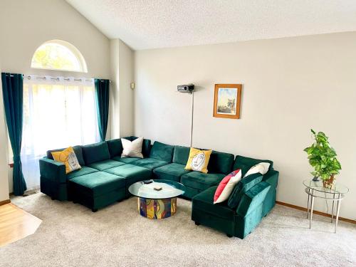 a living room with a green couch and a table at Artsy Home close to USAFA with Fireplace and Patio in Colorado Springs