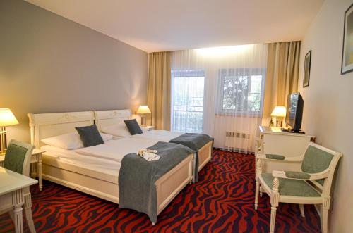 um quarto de hotel com uma cama grande e uma cadeira em Hotel Galant Lednice em Lednice