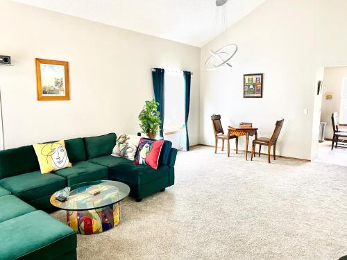 a living room with a green couch and a table at Artsy Home close to USAFA with Fireplace and Patio in Colorado Springs