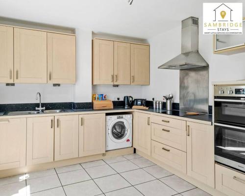 a kitchen with white cabinets and a washing machine at The Penthouse 3 Bedroom Apartment by Sambridge Stays in Watford