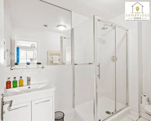 La salle de bains blanche est pourvue d'une douche et d'un lavabo. dans l'établissement The Penthouse 3 Bedroom Apartment by Sambridge Stays, à Watford